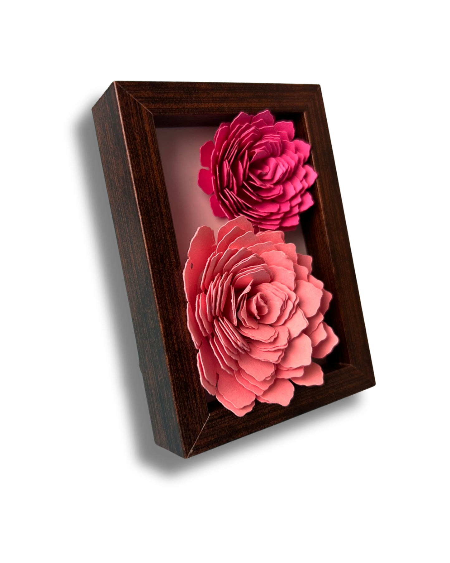 Kleiner dunkelbrauner Bilderrahmen mit zwei Blumen in Pink und rosa vor weißem Hintergrund.