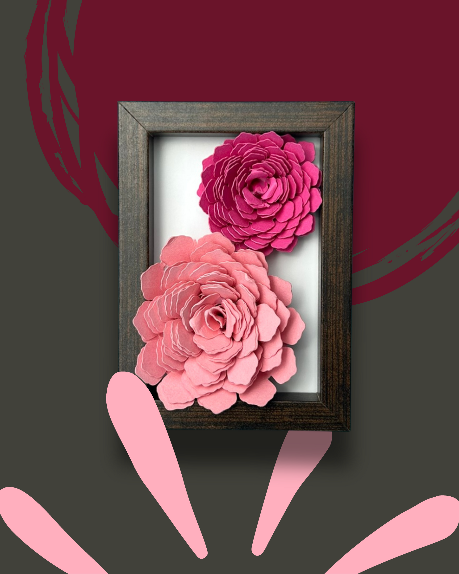 Kleiner dunkelbrauner Bilderrahmen mit zwei Blumen in Pink und rosa vor weißem Hintergrund.