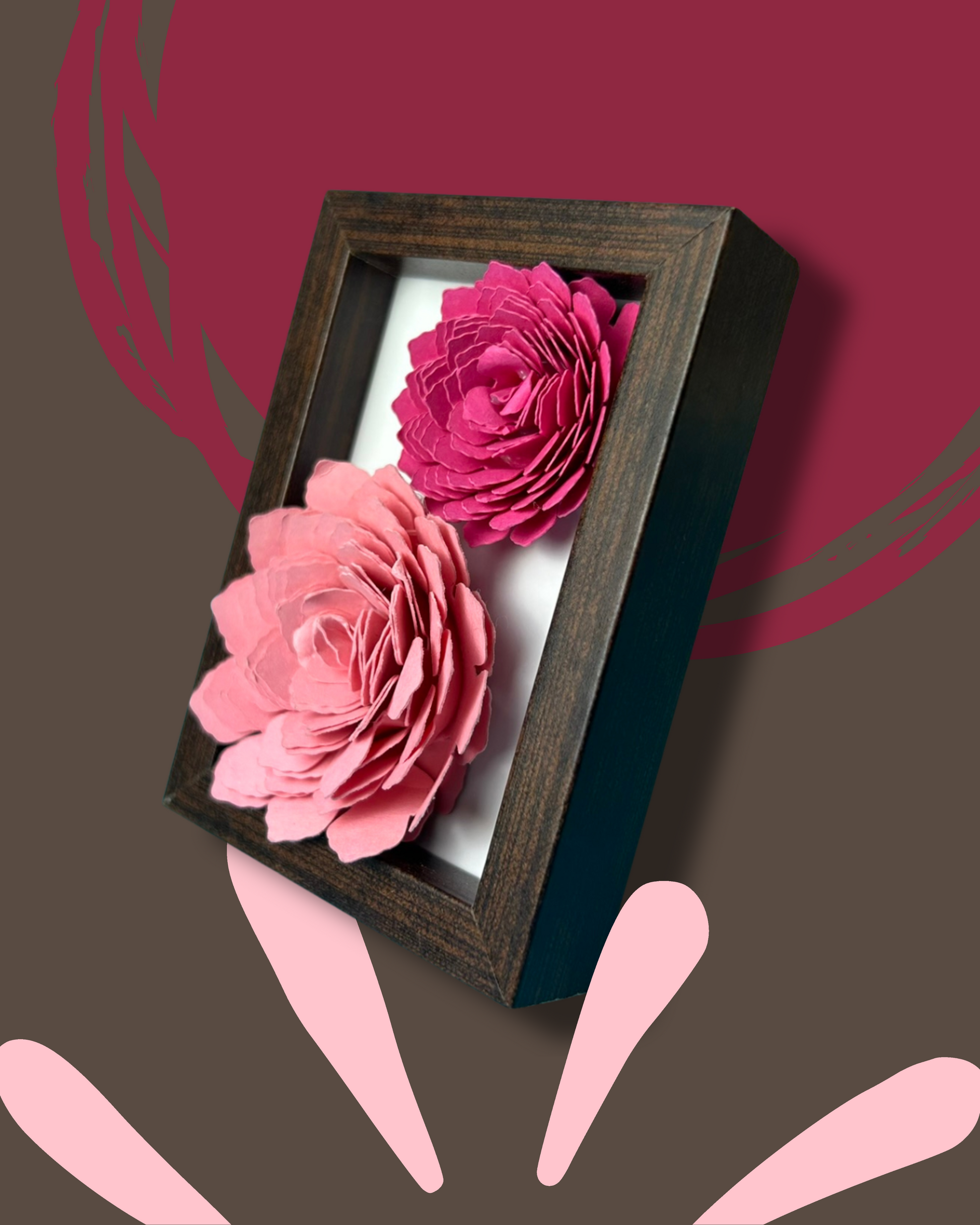 Kleiner dunkelbrauner Bilderrahmen mit zwei Blumen in Pink und rosa vor weißem Hintergrund.